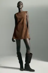 Vestido corto de cuello barco y manga sisa, confeccionado en tejido efecto ante. Presenta un diseño en línea evasé con detalle de pliegues laterales y cierre de cremallera oculta en la espalda.