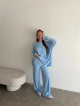 Conjunto de dos piezas compuesto por un buzo de cuello redondo y mangas largas con diseño holgado y un pantalón de corte recto y tiro alto. Ambas prendas están confeccionadas en tejido de punto acanalado.