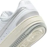 Championes Nike Gamma Force de diseño urbano, con base blanca y detalles en plateado metalizado en el logo lateral y el talón. Presenta una suela de plataforma en tono crema con acabado gris en la parte inferior.