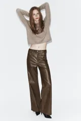 Pantalón de tiro medio confeccionado en tejido efecto piel, con diseño de cinco bolsillos y cierre frontal con cremallera y botón.