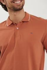 Chomba azul marino de piqué con cuello clásico y tapeta de dos botones. Detalles de ribete blanco en cuello y mangas.