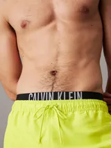 Bañador corto de hombre color amarillo flúor, con cintura elástica negra con logo Calvin Klein en blanco.