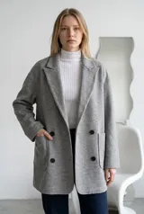 Tapado de paño color marrón, de corte oversize, con solapas clásicas, cierre frontal de doble botonadura y bolsillos laterales de parche.