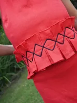 Top corto de cuello halter con volado plisado en el bajo y detalle de cordón.