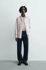 Camisa slim fit de algodón, color beige con rayas verticales blancas. Presenta cuello italiano, manga larga con puño de botón y cierre frontal de botonadura.