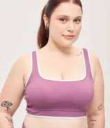 Top deportivo Get Over confeccionado en microfibra color violeta, con escote recto, copa incorporada, breteles anchos y bies contrastante en color blanco. Cuenta con banda acanalada en la base.