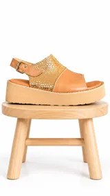 Sandalias de cuero color camel con plataforma y tira trasera regulable. Combinan cuero liso con un sector de textura metalizada dorada con apliques.
