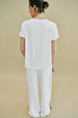 Camiseta de algodón con cuello redondo y manga corta. Presenta un diseño estampado frontal con efecto metalizado plateado sobre fondo rectangular.