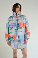 Campera puffer capitoneada con estampado patchwork en tonos pastel y detalles de cuadros.