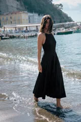 Vestido midi negro con cuello halter y falda acampanada con volumen.