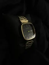Reloj Casio Quartz con caja cuadrada y correa de eslabones en tono dorado. La esfera es de color negro con manecillas y marcadores de hora dorados, y cuenta con una ventana de fecha.