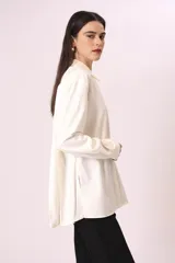 Camisa blanca de corte oversize, con cuello clásico y mangas largas con puños abotonados.