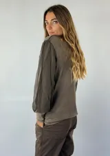 Blusa de color gris con mangas largas abullonadas de tejido traslúcido y cuerpo con efecto lavado.