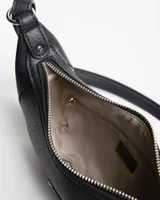 Bandolera de cuero sintético color negro, diseño semicircular con tachas metálicas plateadas en los bordes. Incluye correa ajustable y desmontable, cierre superior y etiqueta colgante con las iniciales XL.