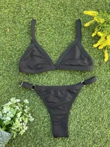Conjunto de bikini negro con corpiño triangular fijo y bombacha colaless con argollas doradas en los laterales.