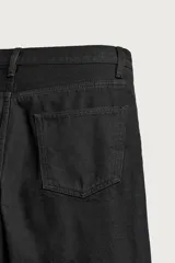 Jeans slim straight fit para hombre, confeccionados en denim de algodón negro sin lavados. Presentan diseño de tiro bajo, pierna recta y cinco bolsillos, con cierre frontal de botonadura.