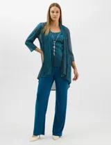 Conjunto de tres piezas compuesto por musculosa, cardigan y pantalón. La musculosa y el cardigan presentan un diseño plisado con hilos metalizados en tonos verdes y azules, creando un efecto tornasolado. El cardigan es de frente abierto con mangas 3/4 y corte fluido. El pantalón es de seda fría en color azul petróleo, con cintura elastizada. Incluye un collar removible.