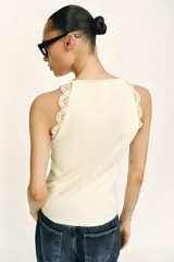 Top negro de punto rib con cuello halter, sin mangas y detalles de encaje a tono en las sisas.