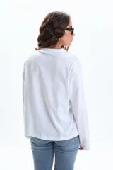 Remera blanca de manga larga con cuello redondo y estampado frontal que dice "BERLIN Athletic Training Dept." con tres estrellas y "URBAN LEGACY 1986" debajo.