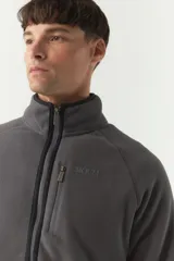 Campera polar gris de poliéster con cuello elevado, cierre frontal, bolsillos laterales con cierre y logo estampado en el pecho.