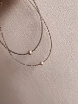 Gargantilla doble con cadena de eslabones plateados y perlas cultivadas.