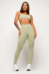 Conjunto deportivo de dos piezas en color verde pistacho, compuesto por un top de tirantes finos con escote recto y una calza larga de tiro alto con detalles de líneas en contraste.