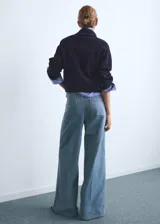 Pantalón de jean estilo denim con corte de pierna ancha y cintura alta. Presenta dos bolsillos de parche en la parte delantera, dos bolsillos traseros, trabillas para cinturón y cierre frontal con botón y cremallera.