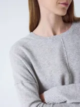 Sweater de cachemira color negro para mujer, con cuello redondo y corte oversized. Presenta costuras externas decorativas, hombros caídos y un diseño ligeramente más largo en la parte trasera con aberturas laterales. Los puños y el bajo cuentan con acabado acanalado.