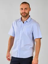 Camisa de manga corta con cuello camisero y botones frontales. El tejido es de color crema con un patrón de cuadros pequeños en negro y marrón.