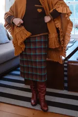 Falda midi de corte recto confeccionada en tejido de lana con estampado de cuadros en tonos tierra y líneas en contraste. Presenta un diseño estructurado con forro interior.
