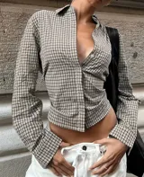 Camisa entallada de manga larga con estampado de cuadros, cuello clásico y cierre frontal con botones. Presenta un diseño con lazo regulable en la espalda para ajustar el calce a la cintura.