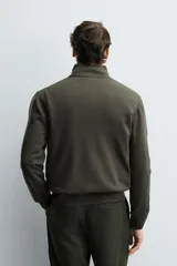 Jersey de punto de corte regular, con cuello perkins y cierre frontal parcial con botonadura. Presenta manga larga y acabados en rib en puños y bajo.