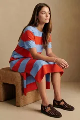Vestido midi de tejido de punto con diseño de rayas horizontales anchas en color rojo y celeste. Presenta cuello redondo, mangas cortas y aberturas laterales en el ruedo.