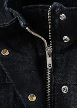 Parka de denim negro de corte largo, con cuello alto, cierre frontal oculto y múltiples bolsillos con solapa en el pecho y los costados. Cuenta con cordón ajustable en la cintura.