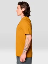 Camiseta de manga corta color mostaza con cuello redondo. Presenta un pequeño logo de Mountain Hardwear en el pecho izquierdo y un gráfico grande enmarcado en la espalda.