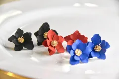 Par de caravanas con forma de flor, con centro dorado y pétalos en color negro, rojo y azul.