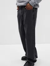 Jean de corte baggy, color negro lavado, con diseño de cinco bolsillos y cierre frontal con botón y cremallera.