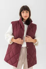 Chaleco acolchado de corte recto y largo medio, con diseño de rombos, cuello alto y cierre frontal con botones a presión.