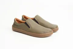 Championes slip-on color verde militar, con capellada de cuero graneado y suela de goma marrón. Presentan elásticos laterales para un calce cómodo y rápido, y costuras decorativas en contraste.