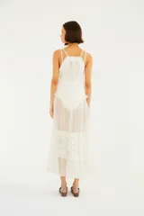 Vestido midi blanco de tirantes dobles, confeccionado con paños de tul plumeti y encaje floral. Presenta escote en V, forro corto interno, volados y un ruedo asimétrico con transparencias.