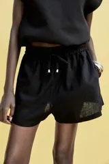 Bermuda color crema confeccionada en lino, de tiro alto con cintura elástica ajustable con cordones y bolsillos delanteros.