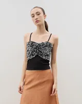 Top de tirantes finos con diseño bicolor, presentando una sección superior con lentejuelas brillantes y una sección inferior de tela lisa, con detalle de frunce central.
