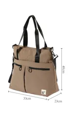 Bolso negro tipo tote de poliamida con doble asa de hombro, bolsillos frontales con cierre y tiradores circulares.