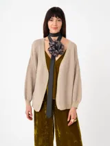 Cardigan tejido color beige con hilo de lurex, manga globo y puños ajustados.