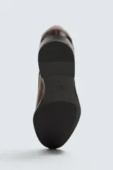 Zapato de vestir de cuero negro, tipo derby, con horma en punta y suela con ligero tacón.