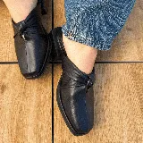 Zueco de cuero vacuno color negro, con diseño de nudo en el empeine y punta cuadrada. Cuenta con un taco bajo de madera y suela de cuero.