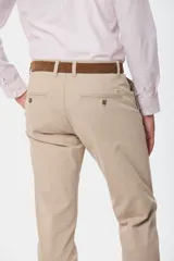 Pantalón de gabardina color marrón claro, corte slim fit, con bolsillos laterales y traseros. Se ajusta a la cintura con cinturón de cuero marrón.