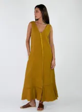 Vestido largo sin mangas, de color mostaza, con escote en V y bolsillos laterales. Presenta costuras decorativas visibles con bordes deshilachados en el frente y en el ruedo.