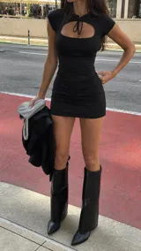 Vestido corto negro entallado al cuerpo, con mangas cortas, escote redondo y detalle de abertura ovalada en el pecho con cordones para atar.