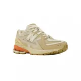 Championes urbanos New Balance modelo 1906, con diseño técnico de running. Presentan una combinación de tonos beige y crema en el cuerpo de malla y superposiciones sintéticas, con detalles en color naranja en la entresuela y logotipos. Cuentan con suela de goma y tecnología de amortiguación.